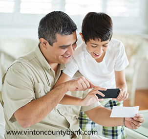 Son And Father Using Mobile Phone To Deposit Check